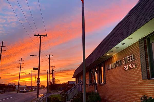 Sunrise over Huntington Steel and Supply Company office building, showcasing brick exterior and 'Huntington Steel Est. 1904' metal letters.